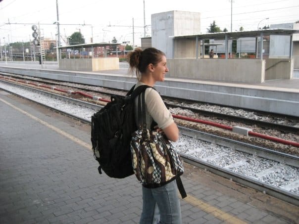 woman wearing a large backpack waiting on a train platform
