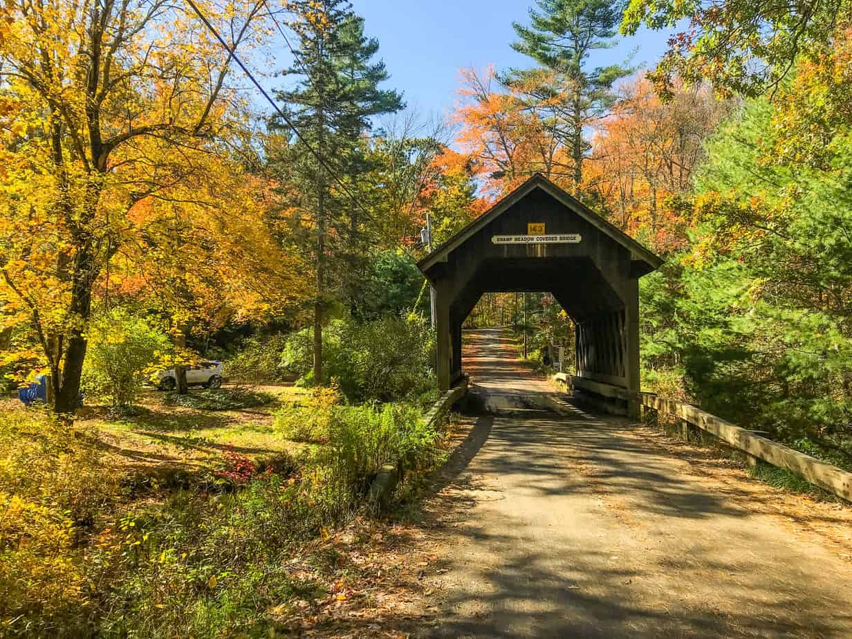 wooden covered bridge surrounded by autumn leaves